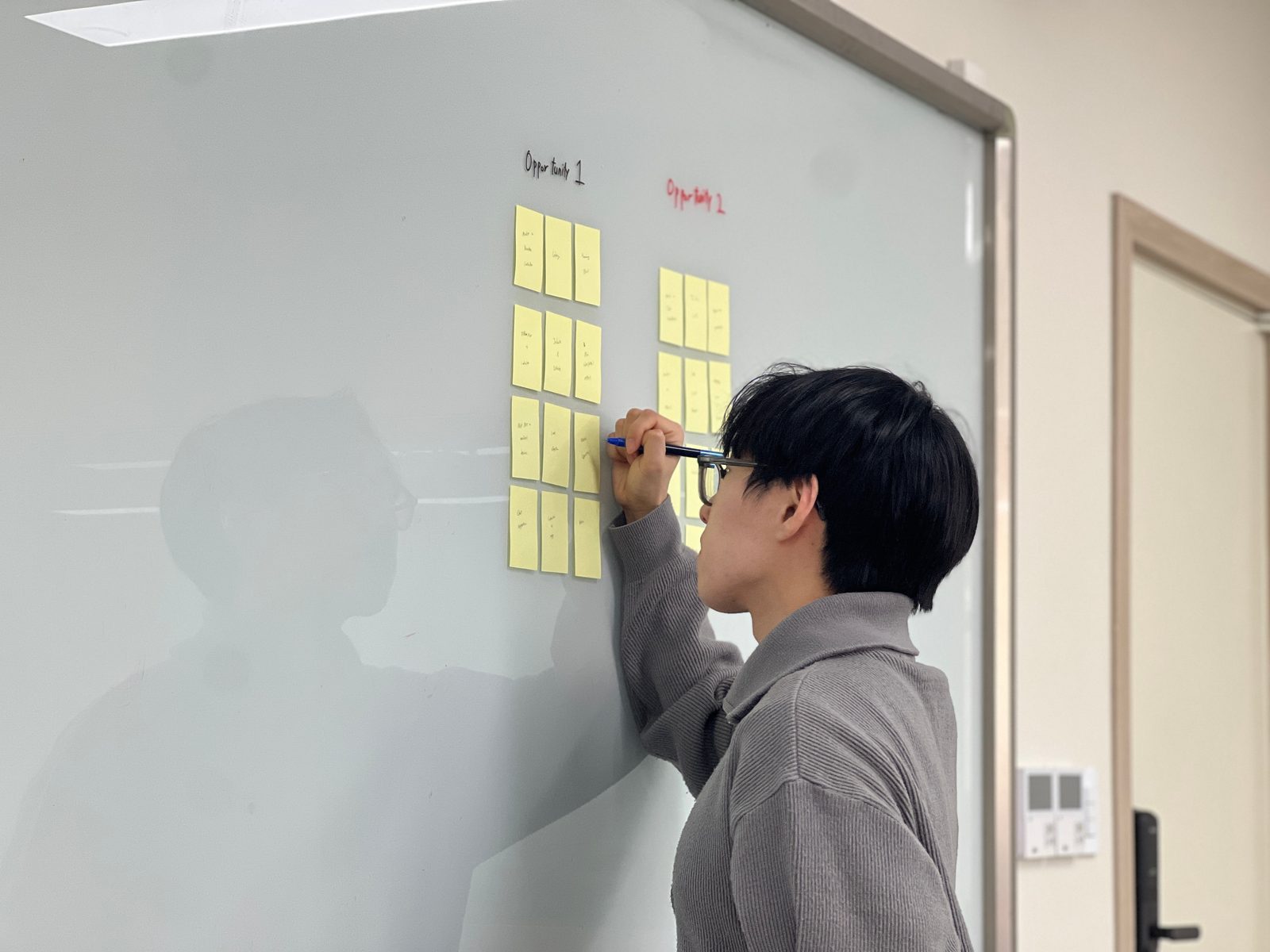 Jin arranging ideas on a whiteboard with sticky notes